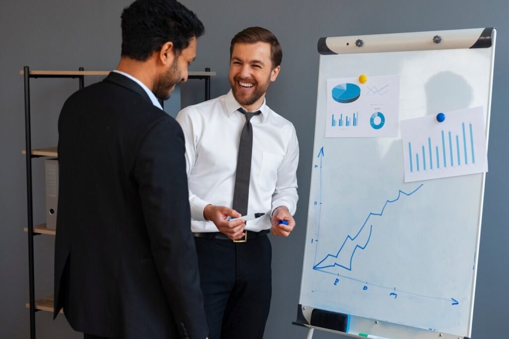 business-person-looking-finance-graphs_23-2150461330 Two businessmen discussing charts on office whiteboard